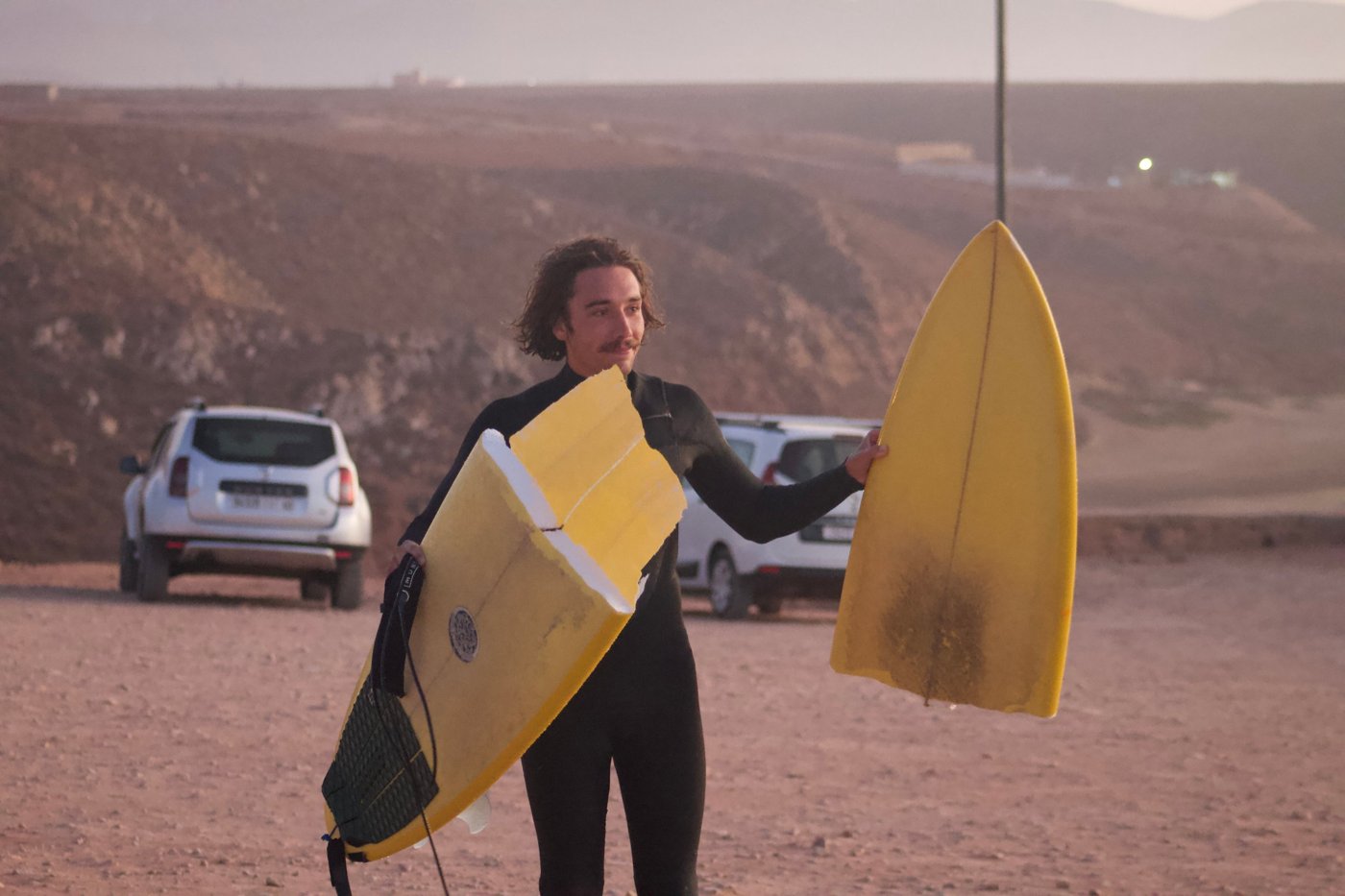 Josh holding his snapped yellow surfboard